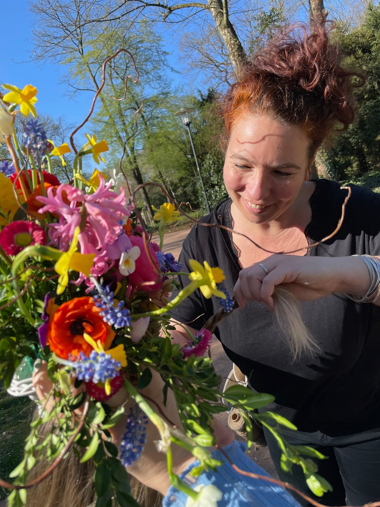Frau mit roten Haaren arrangiert bunte Blumenstrauß im Freien.