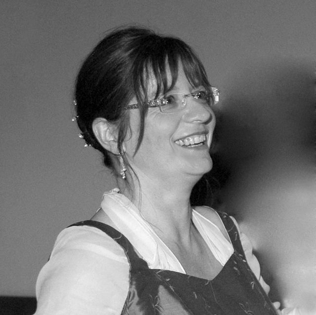 Lächelnde Person mit Brille und Schürze, glückliches Portrait.